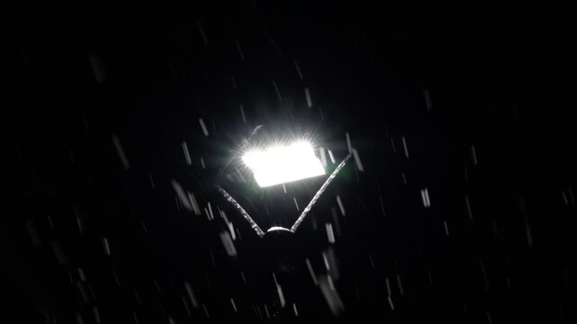 Street light illuminating falling snow during snowstorm at night. Realistic falling snow effect against a dark night sky, ideal for compositing winter scenes, creating a serene and magical atmosphere.