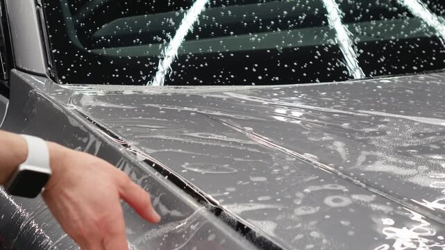 A car wrapping specialist applies a polyurethane film to the car. Detailer smoothes PPF. Car wrapping, detailing, tuning and styling. PPF protective film against chips and scratches. Car protection.