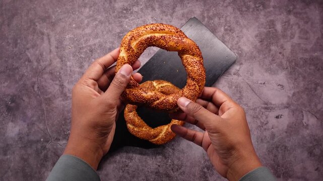 A male hand rotating a simit and putting it on a dark chopping board motion footage.