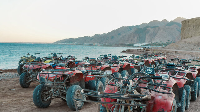 Riding A ATV quadbike vehicles enjoy a summer adventure on the sandy beach near the ocean under a clear sky