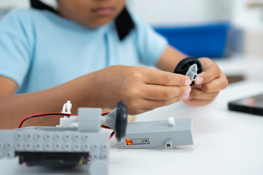 Young girl working on a robot design. Learning robotics basics.
