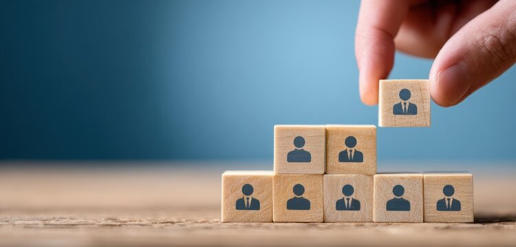 Hand connecting wooden blocks featuring human icons to illustrate team building or organizational structure