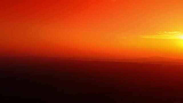 Minimalist sunset sky with deep orange and red gradient haze. Abstract view of a hazy sunset over distant hills with saturated red and orange colors.