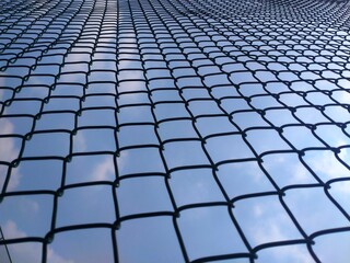 Obraz premium Geometric Chain Link Fence with Blue Sky Background Perspective