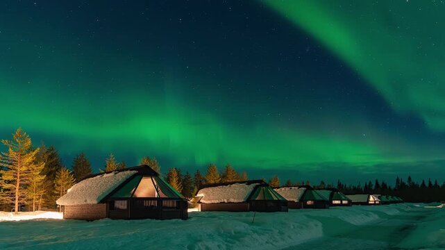 Time lapse : Snow-covered village, Lapland, Northern Finland, rural houses with glass roof, snow covered. Aurora borealis beyond the Arctic Circle. Levi, Finland