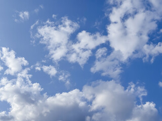 Fototapeta premium Fluffy white clouds scattered across a vibrant blue sky on a sunny day
