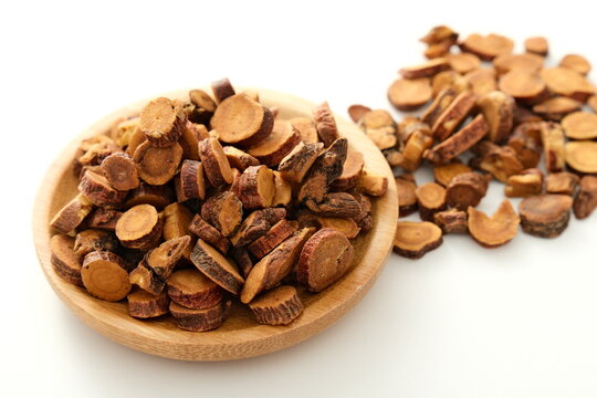 Dried sliced licorice root pieces in a wooden bowl for traditional Chinese medicine use