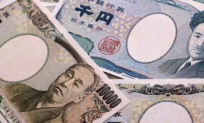 Japanese yen money bills pile on table. Japan banknotes of JPY currency close up. © Larysa