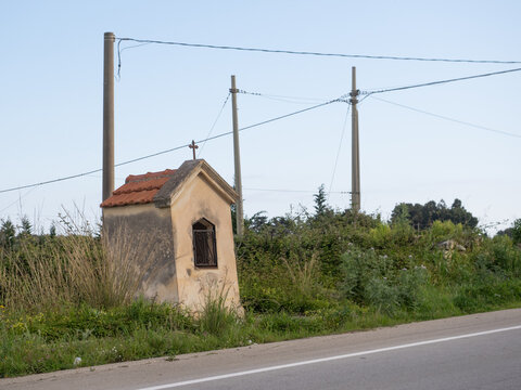 Piccola edicola votiva cattolica incastrata tra pali delle utenze in una strada siciliana