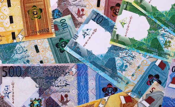 Qatari riyal money bills pile on table. Qatar banknotes of QAR currency close up.