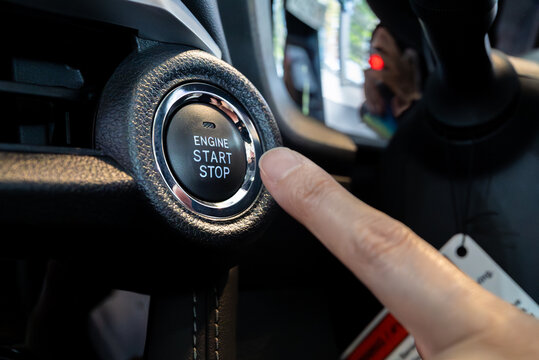 Modern automotive technology. A finger pushes the keyless start-stop button of a new vehicle.
