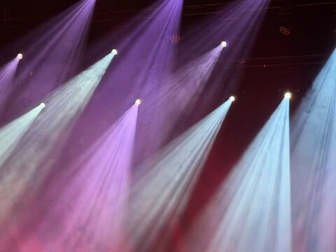 vibrant stage spotlights and beams during concert in white, purple and violet background