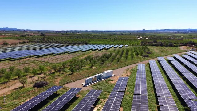 Large-scale ground-mounted solar farm in Spain featuring tilted monocrystalline PV panel rows, central inverter station, and surrounding agricultural land under clear Mediterranean sky