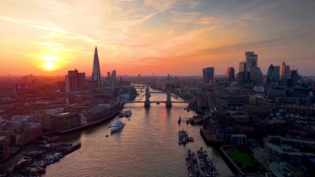 Colorful, panoramic aerial view of the skyline of London, United Kingdom, along the Thames river with City and Tower bridge during a golden sunset