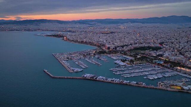 Aerial view of the illuminated skyline of Athens, Greece, with Alimos district, coastal road and yacht marinas during dusk