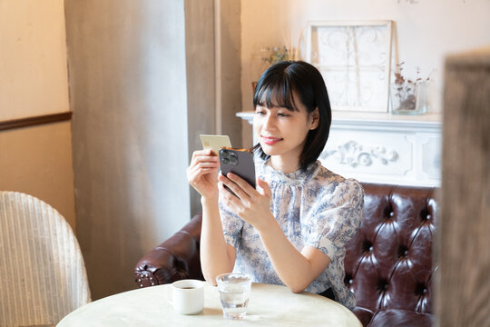 スマホをでカードで決済をしようとしている女性