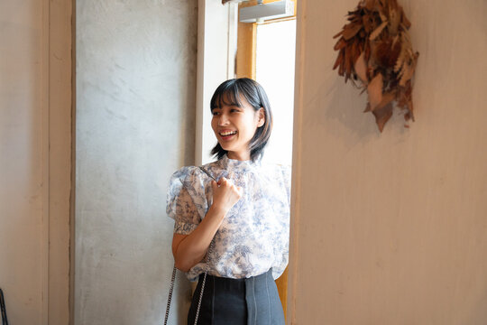 カフェのドアから入って笑っている女性