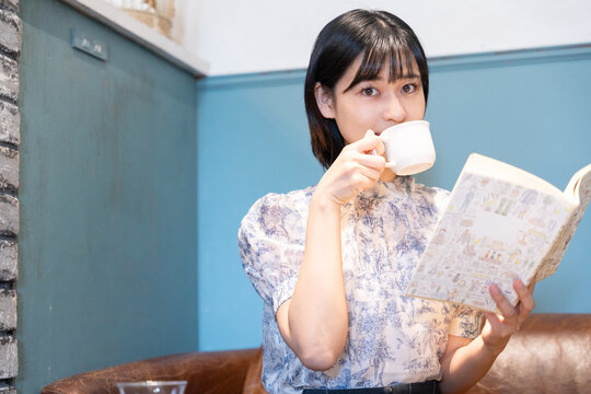 カフェでコーヒーを飲みながら本を読んでいる女性