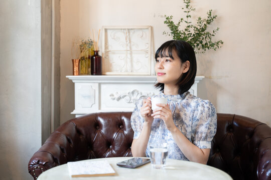 カフェでコーヒーを飲みながらリラックスしている女性