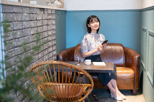カフェでスマホを持って笑っている女性