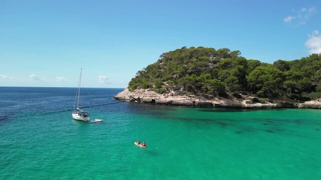 Aerial drone view around a tourist boat and yacht at Cala Macarella and Macarelleta beach, Menorca Island, Balearic islands, Spain. Clean turquoise water