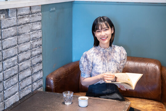 カフェで本を読んでいる笑顔の女性