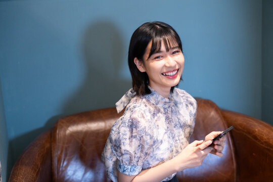 カフェでスマホを持って笑っている女性