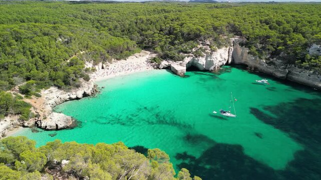 Aerial drone view around a tourist boat and yacht at Cala Macarella and Macarelleta beach, Menorca Island, Balearic islands, Spain. Clean turquoise water