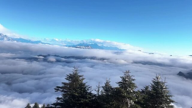A peaceful 1080p timelapse capturing light white clouds weaving through the crevices of a mountain ridge, creating a mystical and zen-like atmosphere.