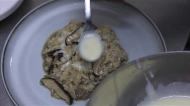 Creamy mushroom risotto being served onto a plate with fresh mushroom slices