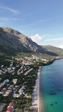 Panoramic view of Barbati Beach in Corfu, Greece. Stunning white pebble beach with crystal clear turquoise Ionian Sea water at the foot of Mount Pantokrator on a sunny summer day.