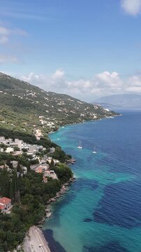 Summer vacation at Barbati Beach, Corfu, Greece. Aerial drone shot of the long pebble coastline, turquoise lagoon, and traditional olive trees under the clear blue sky.