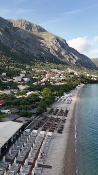 Aerial view of Barbati coastline in Corfu, Greece. Picturesque Mediterranean beach with blue ocean, green mountains, and luxury villas surrounded by olive groves during summer vacation.