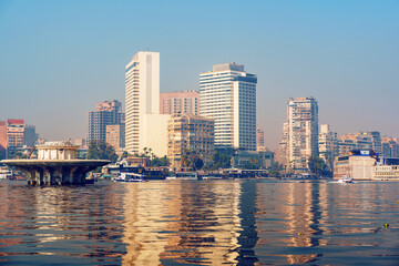 Obraz premium City skyline reflection on the Nile River with modern buildings in Cairo during a clear day
