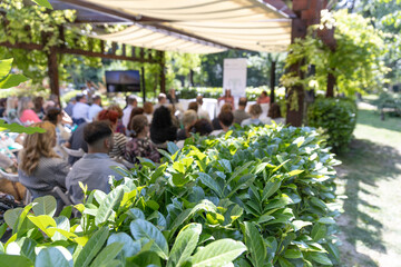 Outdoor business conference with professional audience attending presentation in green garden venue...