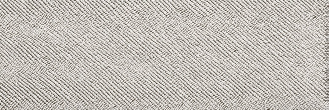A close-up view of an undyed ripstop nylon fabric texture featuring a distinct diagonal weave pattern. The light grey textile surface provides a clean and uniform background.
