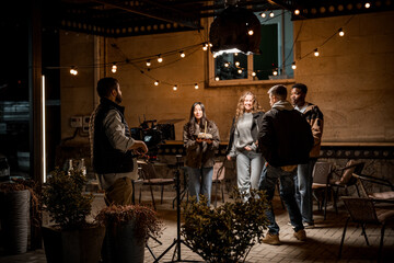 Group of friends filming a scene in an outdoor setting at night with creative lighting and a camera crew present © fotofabrika