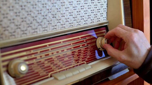 Hand Tuning a Vintage Radio Receiver With Wooden Cabinet and Retro Dial Close-Up