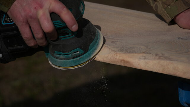 Sanding wood with a vibrating machine. Working with wood, removing old paint with vibration, close-up shot.