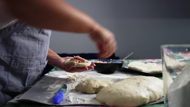 The cook uses a spoon to spoon the minced meat onto the dough. High quality 4k footage