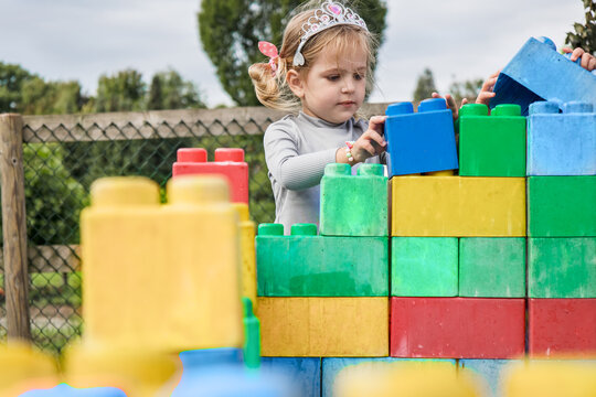 Little girl building colorful blocks tower outdoor play