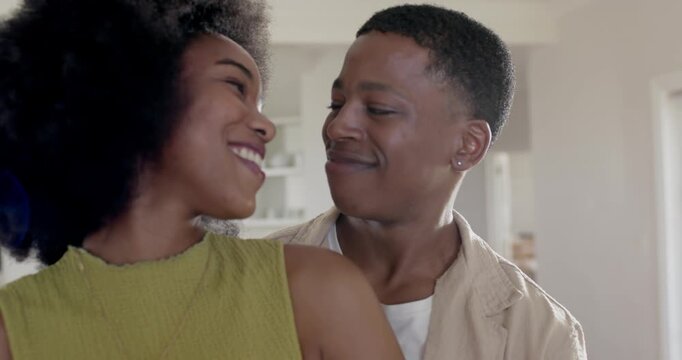 African American couple flirting at home, woman in green top turning, man leaning with ear stud