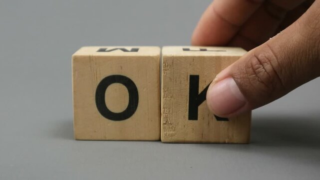 Footage of hand holding wooden letter block with black O and K on front, on gray background with copy space