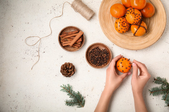 Woman decorating pomander balls on white background