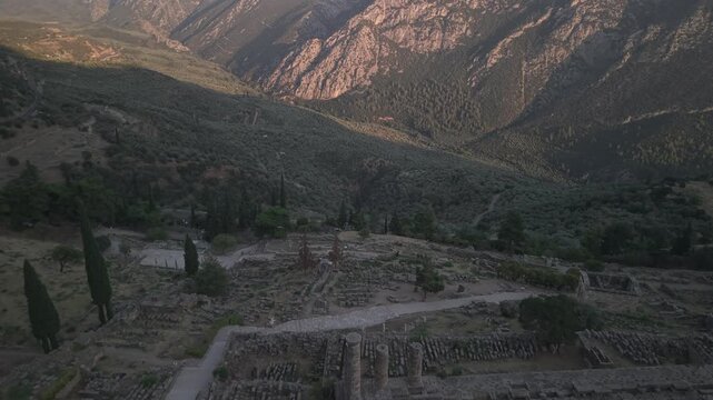 Aerial drone forward shot approaching the Temple of Apollo ruins in Delphi, Greece at sunset.