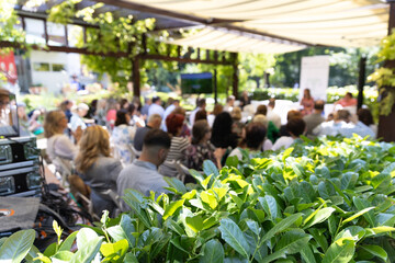 Outdoor business conference with professional audience attending presentation in green garden venue...