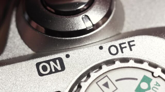 Close up of silver digital camera power switch toggling off to on and back again