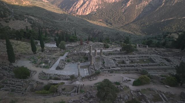 Aerial drone forward shot approaching the Temple of Apollo ruins in Delphi, Greece at sunset.