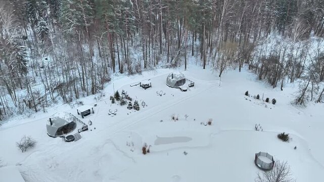Glamping in symmetrical domes in a snow-covered forest. Winter accommodation in nature. A view from a drone