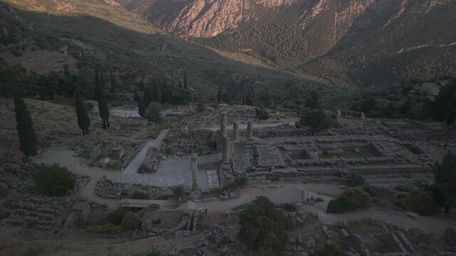 Aerial drone forward shot approaching the Temple of Apollo ruins in Delphi, Greece at sunset.